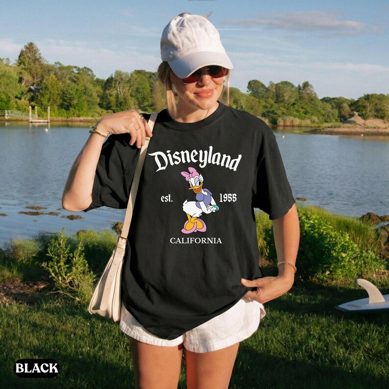 May include: Black t-shirt with the Disneyland logo, Daisy Duck graphic, and the text "est. 1955 CALIFORNIA". The shirt is short-sleeved.