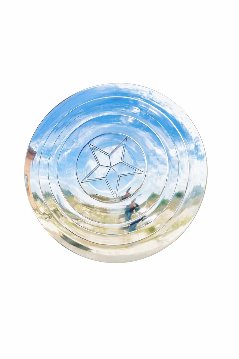 May include: A shiny, silver shield with a five-pointed star in the center. The shield has concentric circles and reflects a blue sky with clouds. A classic superhero accessory.