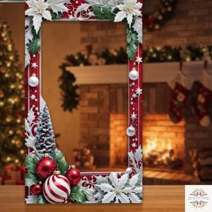 Puede incluir: Un marco de fotos rectangular con un borde rojo decorado con flores de pascua blancas, hojas de acebo verdes, estrellas plateadas y adornos navideños redondos de rayas rojas y blancas. El marco tiene un centro hueco para fotos.