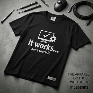 Può includere: T-shirt nero con la scritta "It works... don't touch it." e una grafica di monitor di computer con un segno di spunta e un ingranaggio. La maglietta ha anche la scritta "THE APPAREL FOR THOSE WHO GET IT. IT LEGENDS."