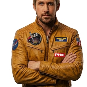 May include: A tan leather jacket with various patches, including a NASA logo and the text "PROJECT HAIL MARY". The jacket features a zip closure and ribbed detailing on the shoulders.