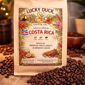 May include: A bag of Lucky Duck Costa Rica whole bean coffee. The bag features a duck with a coffee cup, floral illustrations, and the text "Costa Rica." The bag contains 12 oz (340g) of coffee with notes of tropical fruit, honey, and smooth cocoa.