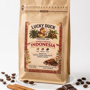 May include: A tan paper coffee bag labeled Lucky Duck Coffee Co. Single Origin Indonesia. The label features a duck illustration, text notes of earthy, dark chocolate, cedar and spice, and states 12 oz | 340g. Coffee beans, cinnamon sticks, and chocolate are nearby.