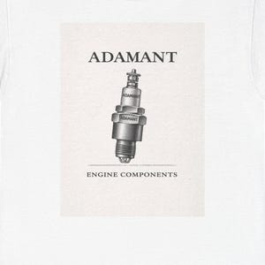 May include: White t-shirt featuring a graphic of a spark plug with the word "ADAMANT" above it and "ENGINE COMPONENTS" below. The spark plug is in shades of gray and black.