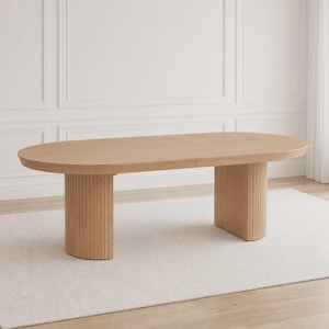 Peut inclure: Une table à manger ovale avec une finition en bois clair. La table présente une surface supérieure lisse et plate et est soutenue par deux bases piédestales semi-circulaires substantielles. Chaque base présente des détails cannelés verticaux.