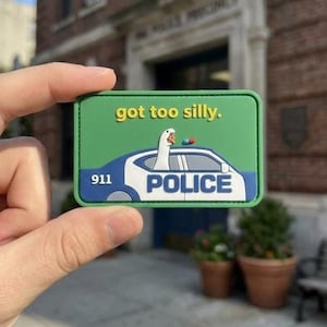 May include: A rectangular green patch featuring a white goose in a blue and white police car. The text "got too silly." is printed in yellow above the car, and "911" and "POLICE" are printed in white on the side of the vehicle.