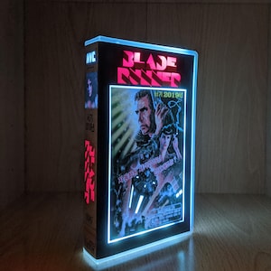 May include: A light-up VHS tape-shaped box with the film title "Blade Runner" in red. The box has a blue neon border and a movie poster image. Includes Korean text on the side.