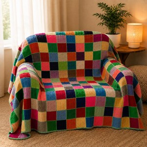 May include: A multi-colored crochet blanket featuring a repeating checkerboard pattern of squares in shades of red, blue, green, yellow, pink, and purple. The textile has a textured, looped surface and is draped over the back and seat of a chair.
