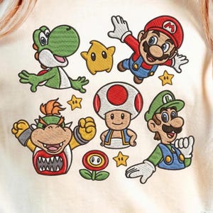May include: Embroidered design featuring characters from the Super Mario Bros. franchise. Includes Mario, Luigi, Yoshi, Bowser, Toad, a Star, and a Fire Flower. The design is in shades of red, green, yellow, and blue on a cream-colored background.