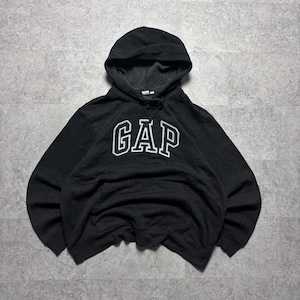Puede incluir: Una sudadera negra de manga larga con capucha que presenta la palabra GAP en letras mayúsculas blancas con borde en el pecho. La prenda incluye una capucha con cordón, puños acanalados, dobladillo acanalado y un bolsillo canguro frontal.