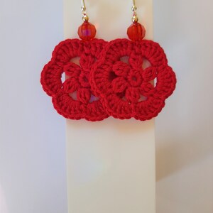 May include: Red crocheted earrings with a red crystal bead on each earring.