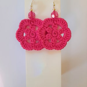 May include: A pair of pink crocheted earrings with a pink crystal bead on each earring.