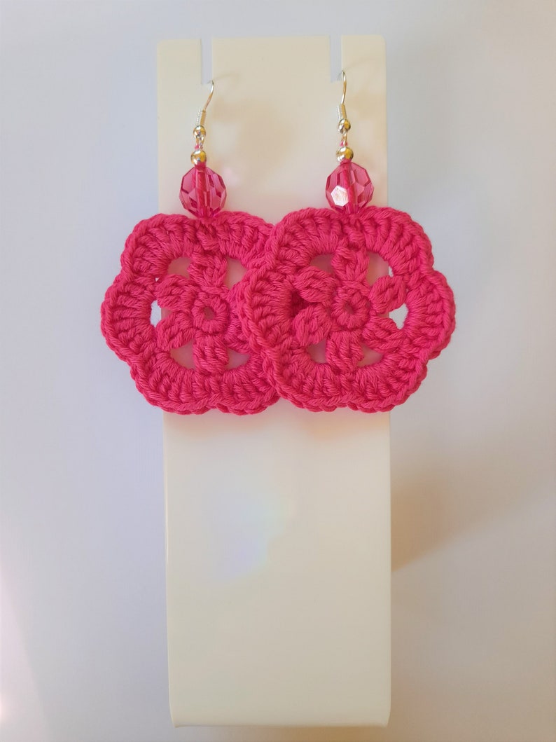 May include: A pair of pink crocheted earrings with a pink crystal bead on each earring.