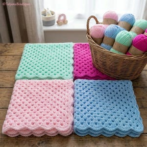 May include: Four pastel-colored crochet blankets in shades of pink, blue, and green are displayed on a wooden surface. A wicker basket filled with yarn in matching colors sits nearby. The blankets have a scalloped edge.