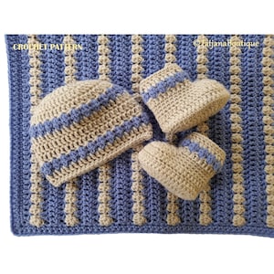 May include: A crocheted baby hat and booties set in beige and blue. The set is laid out on a striped crocheted blanket in beige and blue.