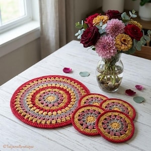 May include: A white ceramic mug with a black handle and the text "But First, Coffee" in a bold, black font. The mug is set against a blurred background, suggesting a cozy setting.