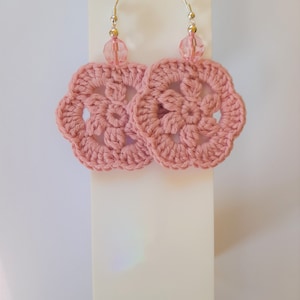 May include: Pink crocheted flower earrings with clear crystal beads hanging from silver hooks.