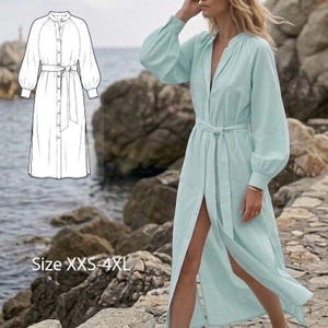 Può includere: Un abito azzurro con bottoni, maniche lunghe e voluminose e una cintura in vita. L'abito presenta uno spacco alto e un colletto alla coreana. A sinistra è presente uno schizzo dell'abito. Il testo sull'immagine recita "Size XXS-4XL".