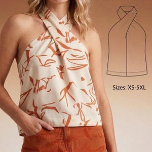 May include: Cream-colored halter top with an abstract orange pattern. The top features a criss-cross design at the neckline. The image also includes a line drawing of the top and the text "Sizes: XS-5XL".