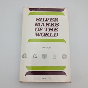 May include: A hardcover book titled Silver Marks of the World by Jan Diviš, published by Hamlyn. The white cover features dark brown text, green horizontal bands, and five small gray silver hallmark icons printed across the center.