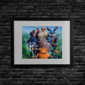 Pode incluir: Impressão emoldurada com personagens do filme de animação "A Origem dos Guardiões". A obra de arte inclui assinaturas e o texto "DO NOT COPY". A moldura é preta e o fundo é uma parede de tijolos escuros.