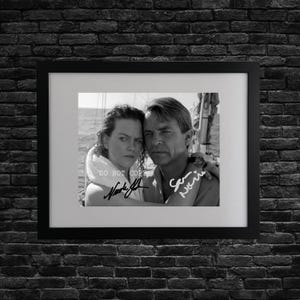 May include: A framed black and white photograph of two people embracing, with visible signatures. The image includes the text "DO NOT COPY". The frame is black, and the background is a dark brick wall.
