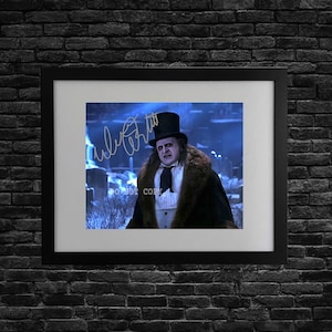 May include: Framed print featuring a character in a top hat and fur-trimmed coat. The image has a blue-toned background and includes an autograph. The frame is black, and the print is mounted on a white mat.