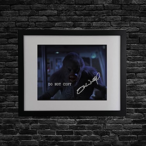 May include: Framed print featuring a creature with a menacing expression, set against a dark background. The print includes the text "DO NOT COPY" and a signature. The frame is black, and the print is mounted on a white mat.