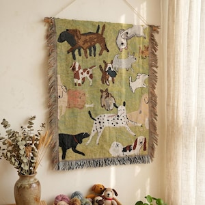 May include: A woven tapestry depicting various dog breeds on a green background. The rectangular tapestry has a fringed edge and is suspended from a wall. The dogs are shown in different colours and poses, creating a whimsical design.