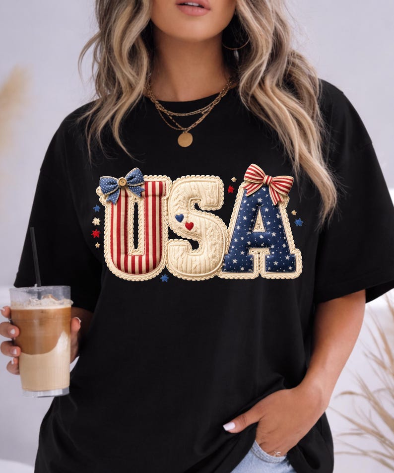 以下が含まれることがあります： 愛国的なデザインの「USA」という文字がプリントされた黒いTシャツ。「U」は赤と白のストライプ、「S」はクリーム色、「A」は白い星の付いた青色です。ゆったりとしたフィット感のTシャツです。