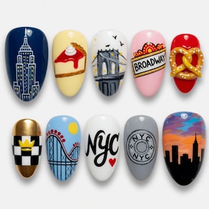 May include: A set of ten painted acrylic nails featuring iconic New York City imagery. Designs include the Empire State Building, a slice of pie, the Brooklyn Bridge, a Broadway sign, a pretzel, a taxi, a roller coaster, the letters "NYC", and a skyline.