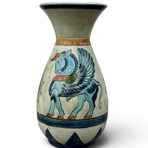 May include: A ceramic vase with a crackled off-white glaze, featuring a hand-painted blue winged horse motif. The design includes orange and dark blue accents, a horizontal band near the base, and a series of dark blue triangles at the bottom rim.