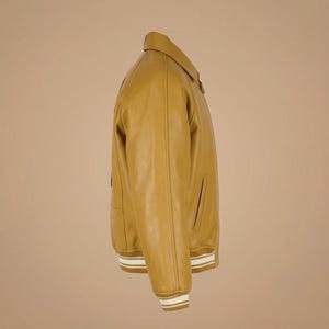 May include: Mustard yellow leather jacket with a classic collar and ribbed cuffs. The jacket features a front zipper and side pockets. The cuffs and hem have white and tan stripes. A stylish outerwear piece.