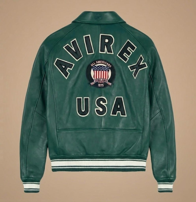May include: Green leather jacket with white and black trim on the cuffs and waist. The back features the word "AVIREX" in white lettering, along with a patch that says "ALL AMERICANS 1975 USA".