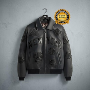 May include: A black leather jacket featuring a full-length front zipper, a pointed collar, and ribbed cuffs and hem. The jacket is decorated with various embossed patches and the text NEW YORK across the chest, along with a KITH logo patch.