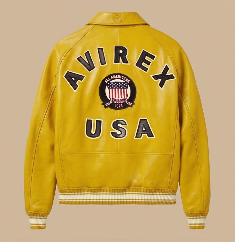 May include: A mustard yellow leather varsity jacket featuring the text AVIREX in black letters arched across the upper back. A circular patch displays an American flag emblem with the text ALL AMERICANS ESTABLISHED 1975. The word USA appears below.