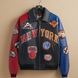 May include: A black, red, and blue leather jacket with "NEW YORK" and basketball-themed patches. The jacket features a zip-up front, a collar, and the "AVIREX" logo. The sleeves are red and blue.