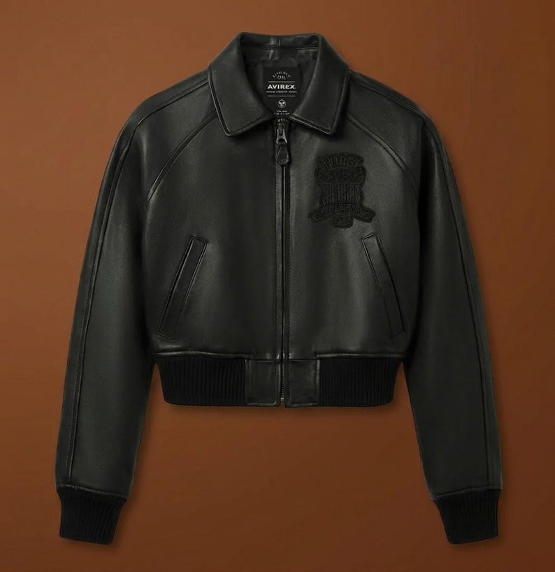 Puede incluir: Chaqueta bomber de cuero negro con cremallera, cuello y pu&ntilde;os y dobladillo de canal&eacute;. Cuenta con un parche en el pecho y la marca "AVIREX" en el cuello.