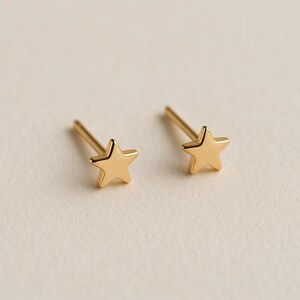 May include: A pair of gold star-shaped stud earrings with a polished finish. Each earring features a five-pointed star design attached to a straight post, showcasing a smooth, reflective surface and a simple, clean aesthetic for everyday wear.