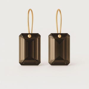 Puede incluir: Un par de pendientes dorados con piedras de cuarzo ahumado rectangulares y facetadas. Los pendientes tienen un diseño sencillo con un gancho dorado y un pequeño acento dorado en la parte superior de cada piedra. El fondo es blanco.