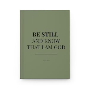 Könnte beinhalten: Ein Notizbuch mit festem Einband in Salbeigrün. Auf dem Cover steht in schwarzer Schrift "BE STILL AND KNOW THAT I AM GOD", darunter "Psalm 46:10". Das geschlossene Notizbuch hat ein schlichtes, minimalistisches Design.