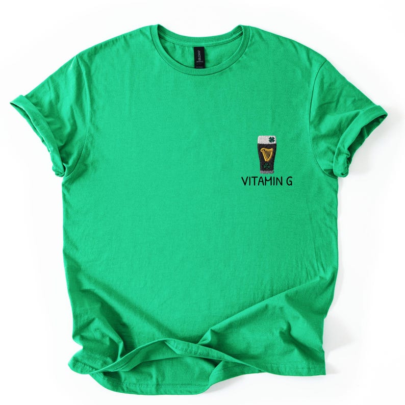 May include: A bright green t-shirt with rolled-up sleeves. The shirt features a small graphic of a dark pint of beer with a harp and shamrock, and the text "VITAMIN G" below the graphic.