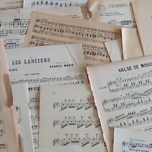 Può includere: Una collezione di spartiti vintage color bianco sporco sovrapposti. I fogli presentano notazioni musicali, pentagrammi e titoli stampati in nero, tra cui Les Lanciers e Valse de Moscheles, che mostrano segni di invecchiamento e usura.