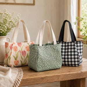 May include: Three fabric tote bags with two handles each. The first bag features a pink and orange tulip print on a cream background. The second bag is green with a small white floral pattern. The third bag has a black and white gingham check pattern.