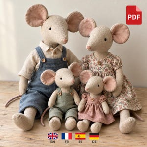 May include: A family of four stuffed mouse dolls made of beige fabric. The two larger mice wear a blue denim overall set and a floral print dress. The two smaller mice wear a sage green overall set and a solid dusty pink dress.