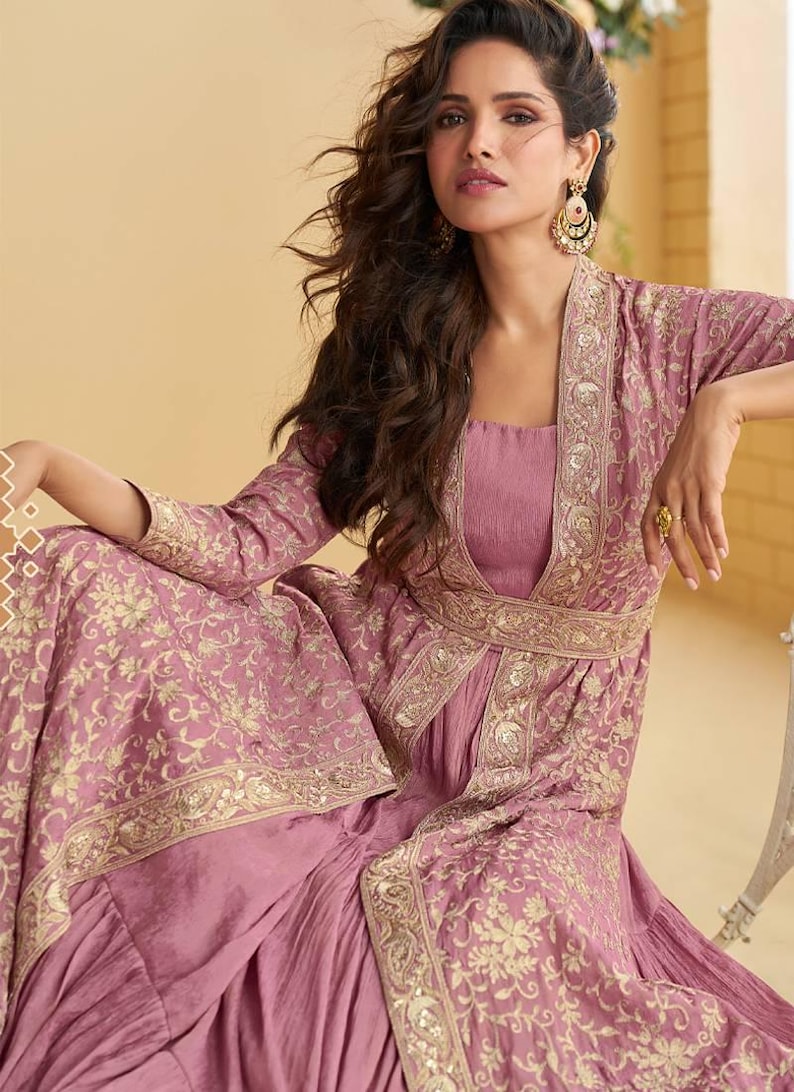 May include: A mauve embroidered outfit, comprising a long-sleeved jacket and dress. The jacket and dress feature gold floral embroidery. This traditional style outfit is suitable for special occasions and celebrations.