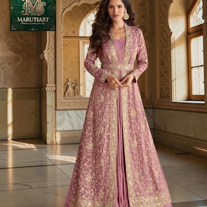 May include: A mauve-coloured gown with gold embroidery and a matching long jacket. The jacket has gold trim and a cinched waist. The image includes the Marutitart logo in the upper left corner.