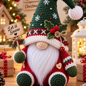 Peut inclure: Une figurine de gnome au crochet portant un grand chapeau vert avec des broderies de flocons de neige blancs et un pompon blanc. Il a une longue barbe blanche, un corps rouge et des pieds verts. Il tient un panneau en bois Let it Snow.