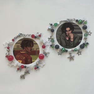 May include: Two beaded bracelets with circular portraits. One features a figure in a red and gold jersey with the name "POTTER" on the back. The other bracelet has a portrait of a person in a green jacket. Both bracelets have silver-toned chains and decorative beads.