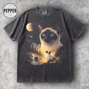 May include: Dark grey t-shirt with a Siamese cat design, a moon, waterfall, and forest scene. The graphic includes a large cat face with blue eyes and a smaller cat figure. The word "PEPPER" is in a circle at the top left.